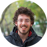 Photo of a close-up shot of George
										  Boumis on a green blurred trees
                                          background. George Boumis has curly
                                          brown hair, wears rectangular
                                          bordeless glasses. Sports a mustache
										  and beard. Wears a black jacket.